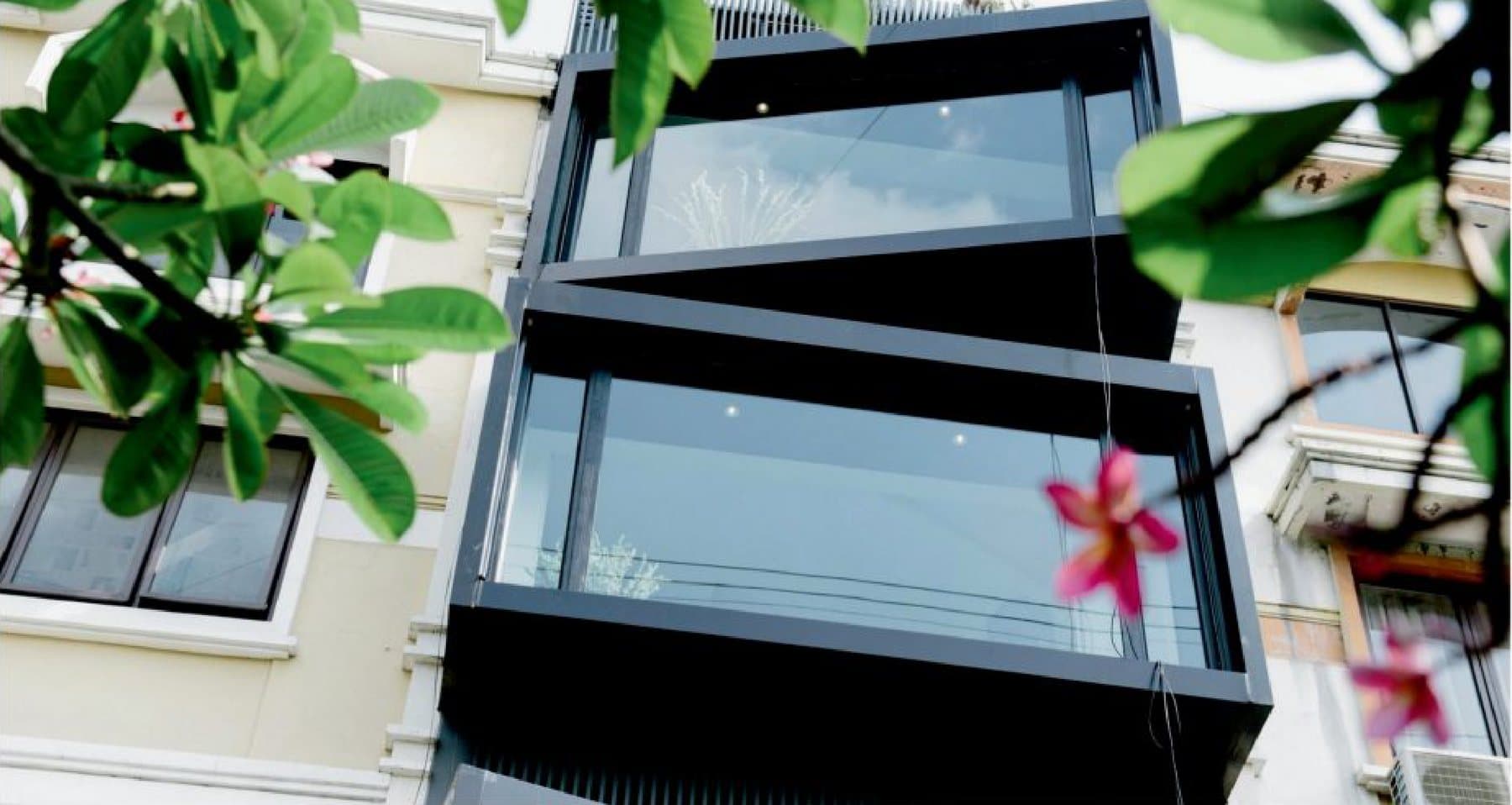 The Surabaya showroom, glazing in crisp aluminium framed by frangipani