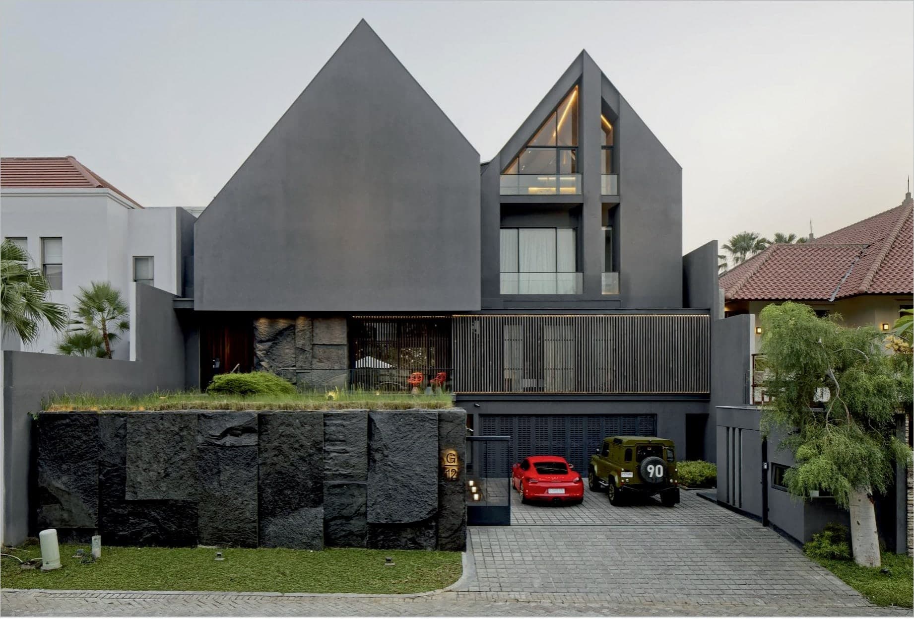 Twin charcoal gables above a base of split natural stone — the street elevation.