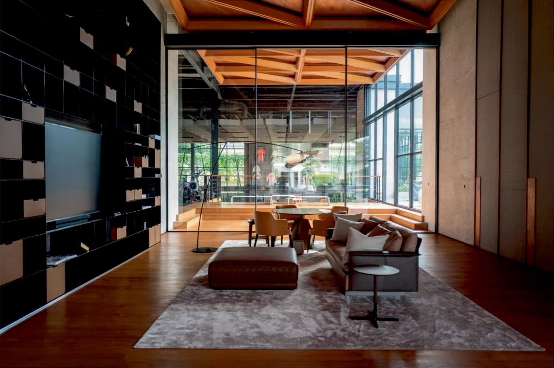 A double-height living room, opened fully to the garden through frameless Fusion glazing.
